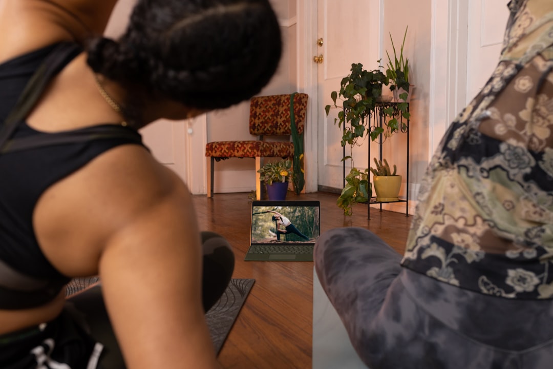 Woman doing yoga following online class on TV - a woman sitting on a chair in a living room