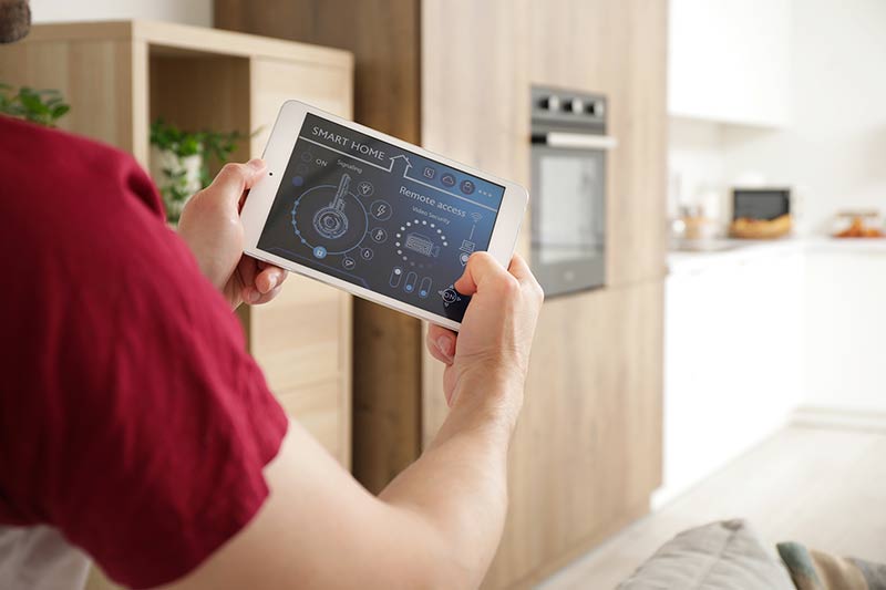 Person controlling smart kitchen appliances with tablet - How Much Does a Smart Home Cost? (2025)